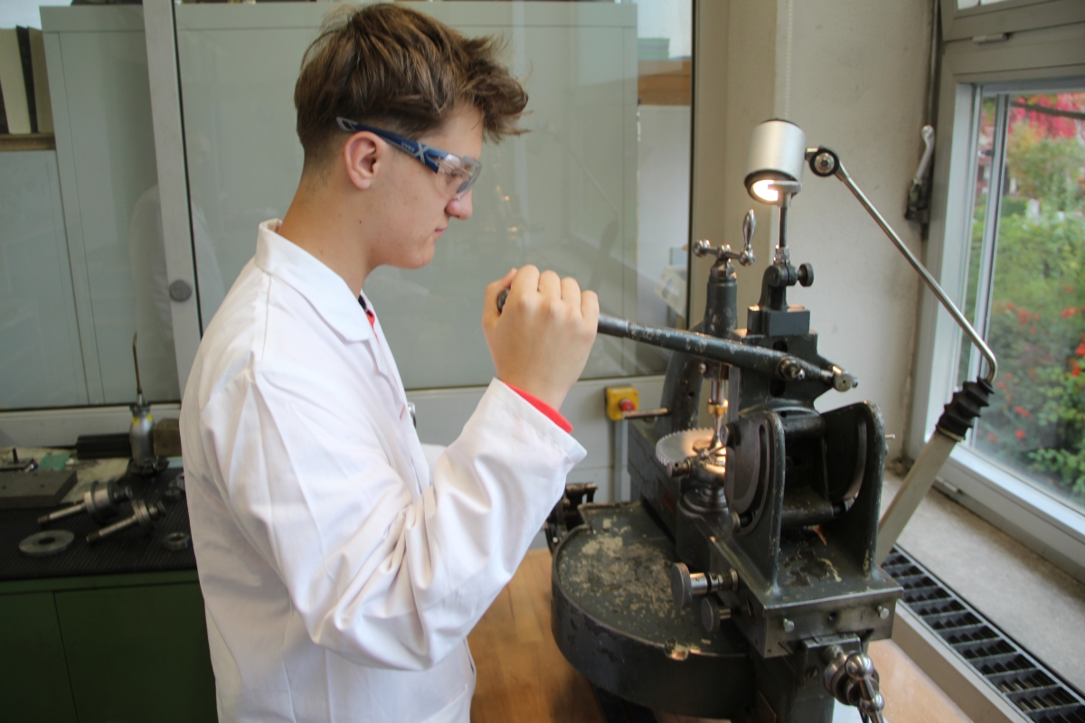 Fineas Dilger, Uhrmacherschüler im zweiten Lehrjahr an der Feintechnikschule Schwenningen, demonstriert, wie die Räderfräsmaschine aus dem Jahr 1956 funktioniert. Foto: Mareike Kratt